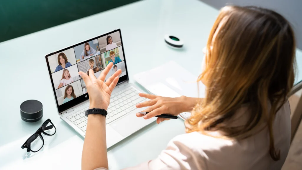 Teacher on a video call with several students on her laptop screen