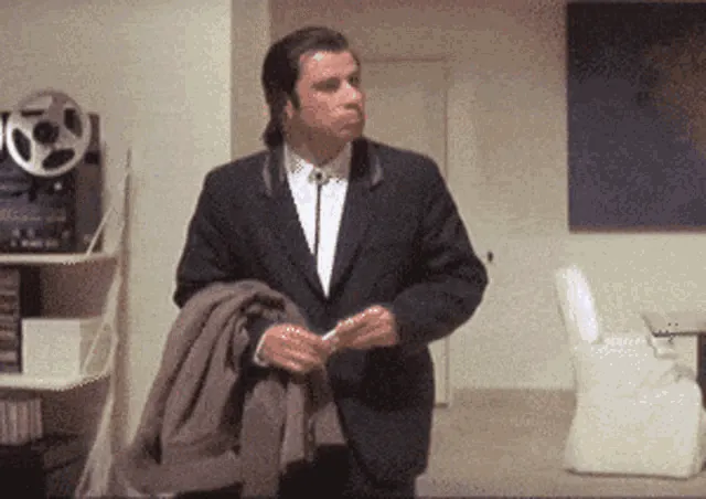 GIF of a man in a suit looking around, confused