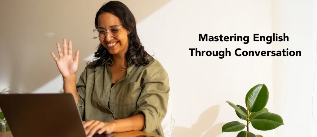 Smiling woman waving at her laptop with the text 'Mastering English Through Conversation'