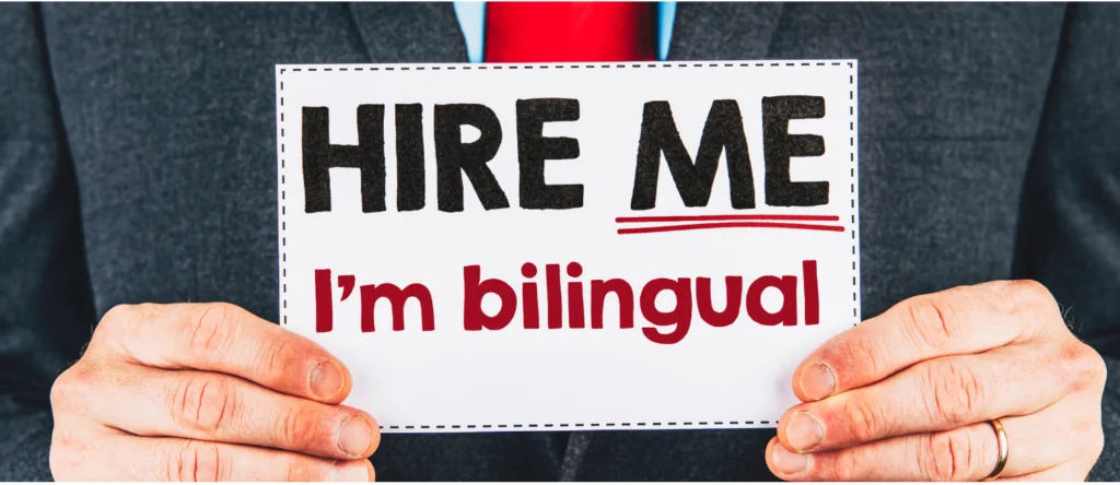 Persona en traje sosteniendo un cartel que dice 'Hire me, I'm bilingual'