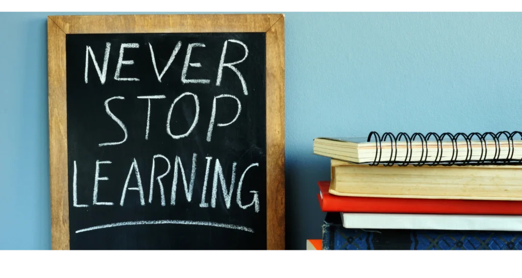 Chalkboard reading 'Never stop learning' next to a stack of books